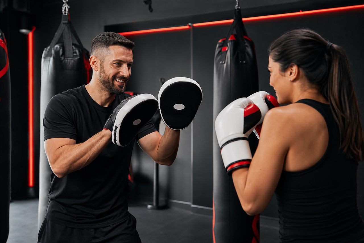 Coach helping a member learn boxing mitt work